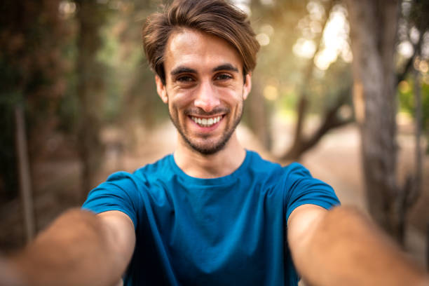 istock Young smiling caucasian man taking selfie in the forest looking at camera. 1423903548