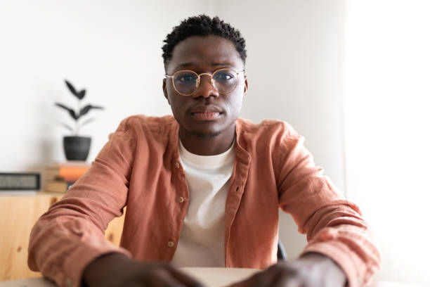 istock Black young man looking at camera with serious expression during video call. 1423903626