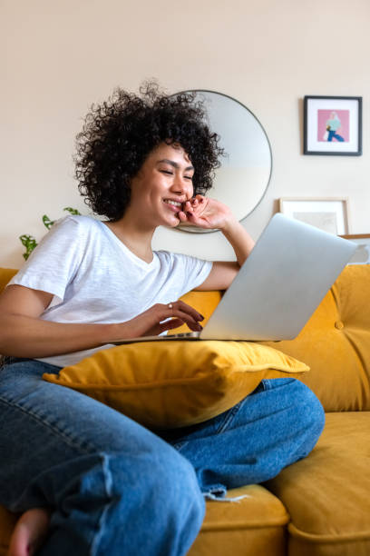 Happy African American woman having fun using laptop at home. Laughing watching funny online videos. Happy African American woman having fun using laptop at home. Laughing watching funny online videos. Technology concept using laptop home stock pictures, royalty-free photos & images