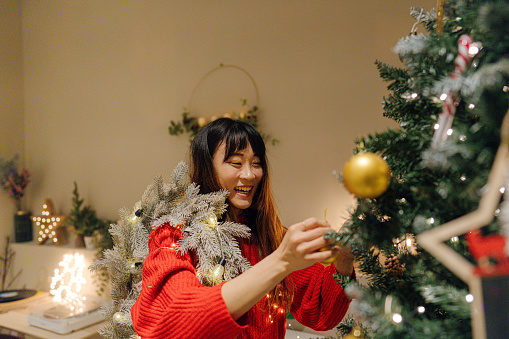 Photo of a young woman decorating her Christmas tree for Christmas and  New Year's holidays