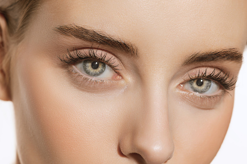 Ojos azules y formas perfectas de cejas. Retrato de cerca de una hermosa joven mirando a la cámara. Concepto de cosmética, maquillaje, tratamiento ecológico, cuidado de la piel. photo
