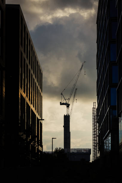 A tall construction crane building tall skyscrapers in a city in a regeneration and industry investment image