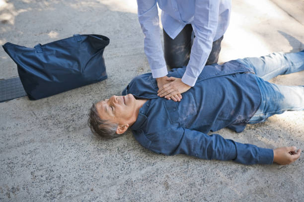 mujer dando primeros auxilios a un hombre mayor - human hand help pain heart attack fotografías e imágenes de stock