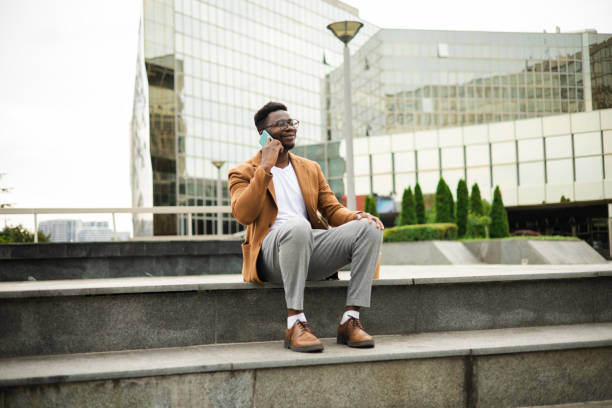 istock Young African businessman  taking a break and talking on mobile phone 1423925986