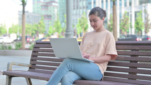 istock Busy Indian Woman Using Laptop Outdoor 1423926466