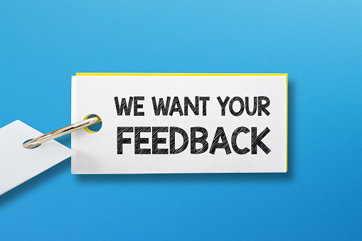 We Want Your Feedback written in note paper on blue background