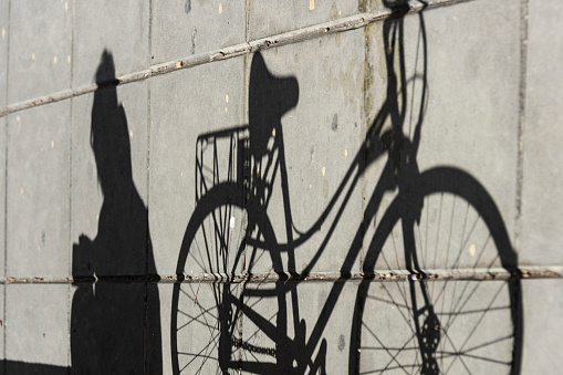 Shadow projected on the floor, of a Woman seated, with her bike at the side, the day september 7, 2022, in the city of Rosario, Santa Fe province, Argentina.