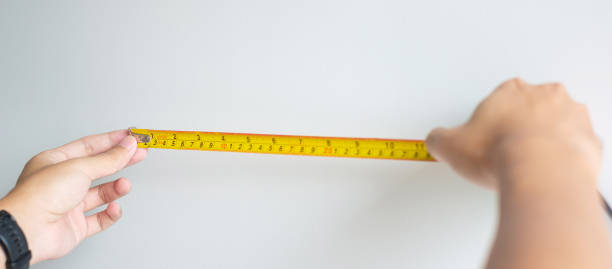istock Man hand using tape measure for measuring with wall backgrounds at home. DIY, Interior design, repairing and improvement home or apartment concepts 1423931495