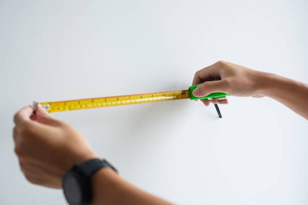 istock Man hand using tape measure for measuring with wall backgrounds at home. DIY, Interior design, repairing and improvement home or apartment concepts 1423931505