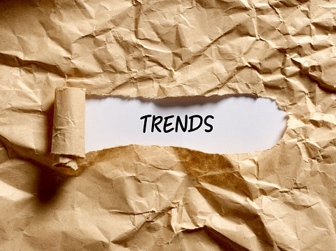 The word trends written under a brown torn paper. Discovering the current popular trends concept.