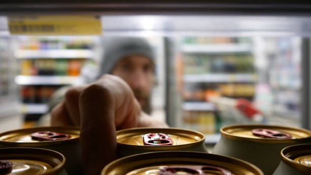 Close-up of beer cans in a supermarket refrigerator and a male buyer takes one Many beer cans in a supermarket fridge close-up and a man takes one grocery shelf cans stock pictures, royalty-free photos & images