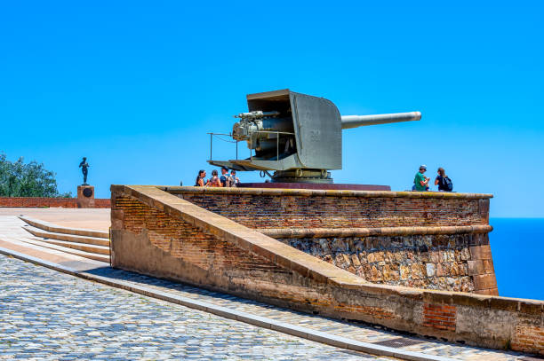 Barcelona, Spain - August 25, 2022: People standing on an elevated area overlooking the sea.  There is an old maxim machine gun in the center of the area.