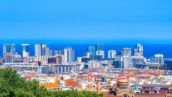 Barcelona, Spain - August 25, 2022: Scenic view of a city with modern buildings on a blue sky background. There are no people on the scene.