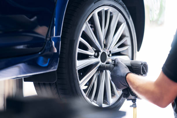Mechanic changing car wheel in auto service using pneumatic wrench stock photo