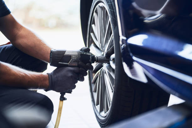 Closeup of car mechanic changing car wheel tire with pneumatic wrench in auto service stock photo