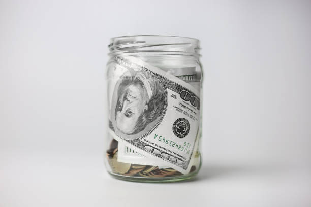 istock Dollars in a glass jar with coins on a white background. Money saving concept 1423937653
