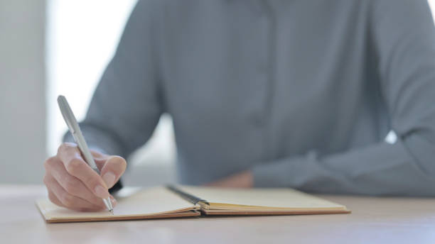 istock Close Up of Woman Writing on Notebook 1423938230