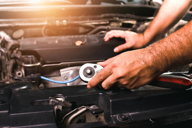 istock The mechanic is holding a metal socket wrench and putting his hand on the engine compartment 1423944977