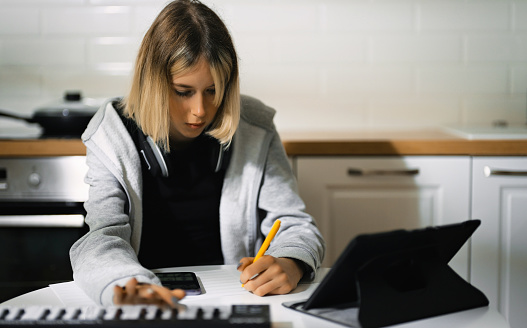 Teenage girl writing composing music at home.