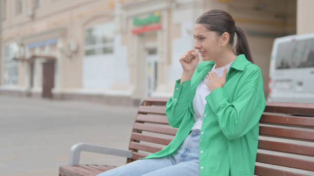 istock Hispanic Woman Coughing while Sitting on Bench Outdoor 1423946893