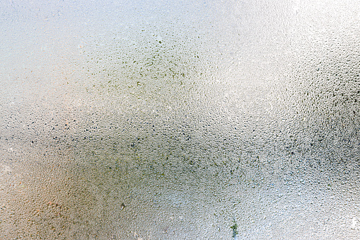 Misted glass, silver rain drops dew drops on transparent glass window. Wet misted glass with drops of water and dew.