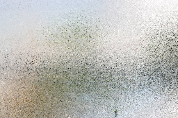 Misted glass, silver rain drops dew drops on transparent glass window. Wet misted glass with drops of water and dew. stock photo