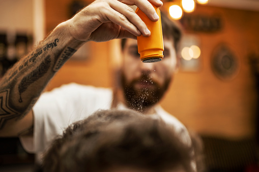 Barber throwing talcum powder on the hair of a customer