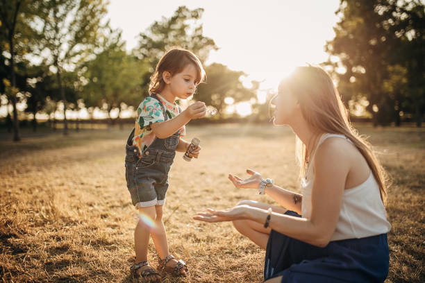 istock Mother And Daughter Having Fun While Blowing Bubbles Together Outdoors 1423951199