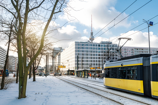 yellow street car approaching station in snowy central berlin in front of TV-Tower
