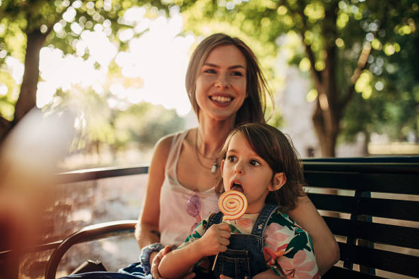 young mother and daughter ride on tour bus and eating lollipop - bus family travel destinations women imagens e fotografias de stock