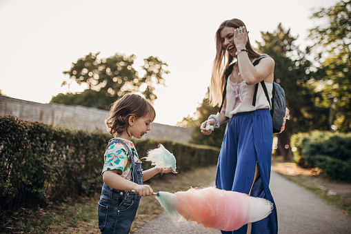 Mother and daughter eating cotton candy in the public park
