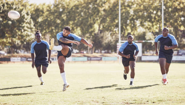 Close up of unrecognizable sportsman kicking the ball at the beginning of rugby match on playing field.