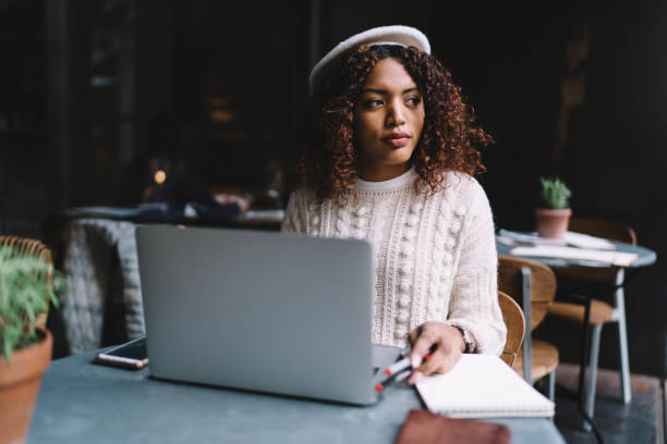istock Young thoughtful ethnic woman working on laptop in cafe 1423961042