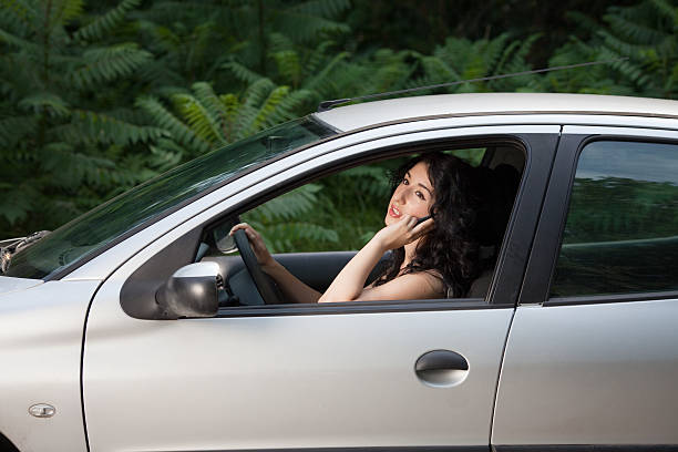 женщина вождение и разговаривать по телефону - car phone стоковые фото и изображения