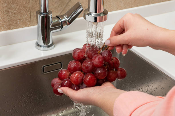 istock Girl washes red grapes in the kitchen 1423966020