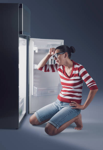 istock Desperate hungry woman and empty fridge 1423970908