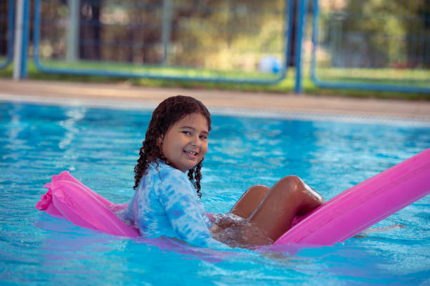 istock Child floating on a pink pool raft, enjoying swimming pool. 1423971133