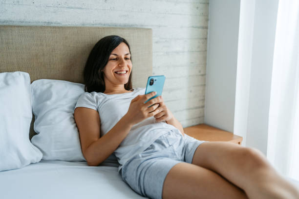 istock Young Woman Using Phone In Bed In The Morning 1423972297