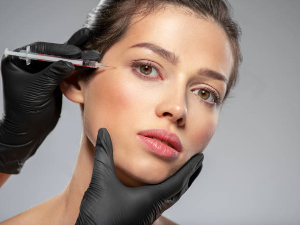 Caucasian woman getting botox cosmetic injection in forehead. Woman gets botox injection in her face stock photo