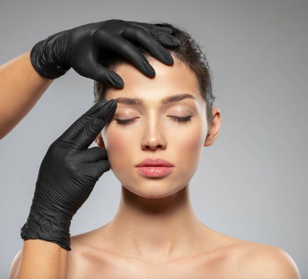 整形手術前の顔の皮膚チェック。美容師は女性の顔に触れる。医師は整形手術の前に皮膚をチェックします。美容トリートメント。整形手術の医師は手で患者の顔に触れています - wrinkle treatment doctor surgeon human hand ストックフォトと画像