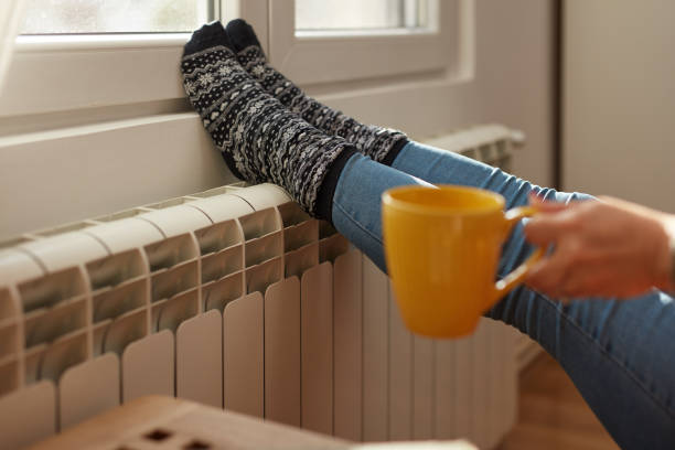 istock Woman heating feet on a chilly winter day, energy and gas crisis, cold room, heating problems. 1423972757