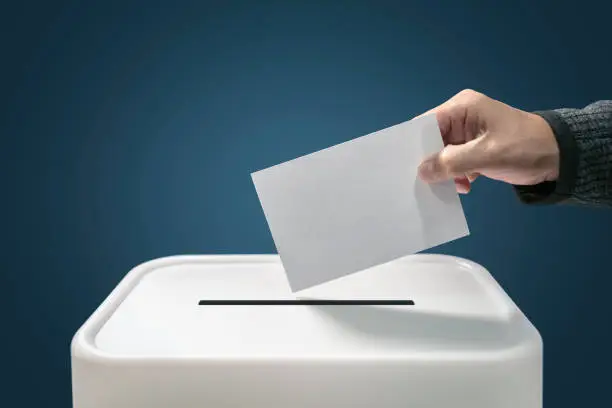 Man putting a ballot paper envelope into a voting box concept for election, freedom and democracy