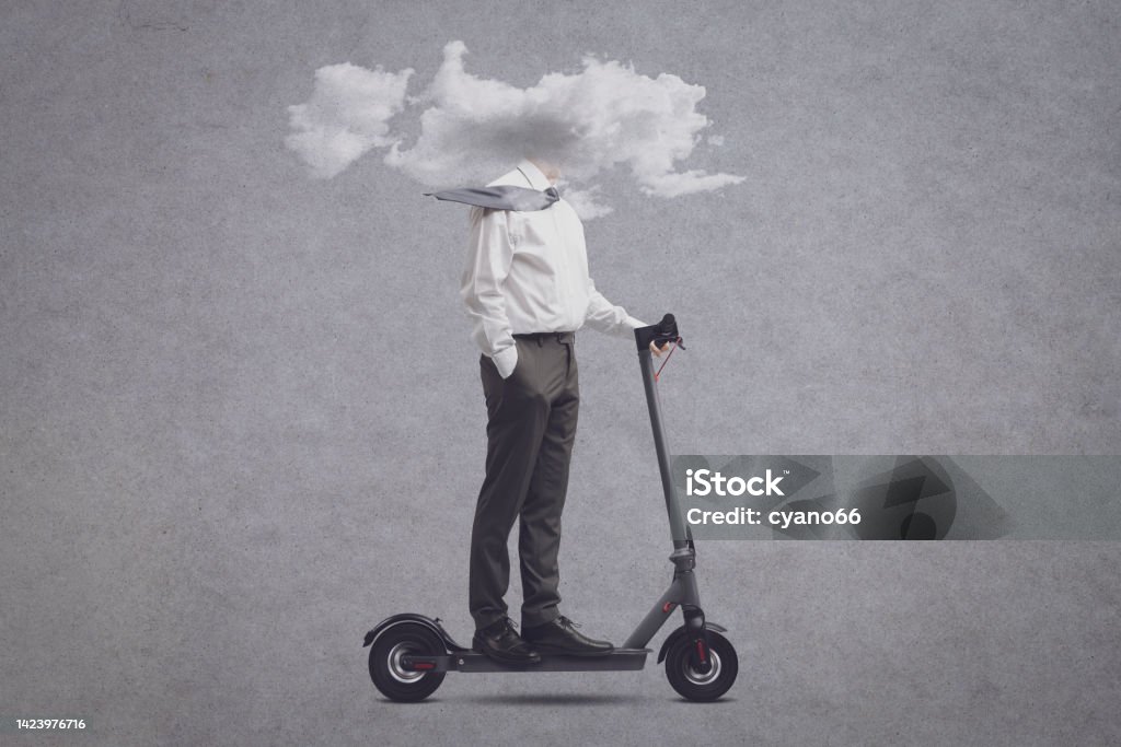 Businessman with head in a cloud riding an electric scooter Businessman riding an electric scooter with his head in a cloud: isolation, distraction and mental fog concept Brain Fog Stock Photo