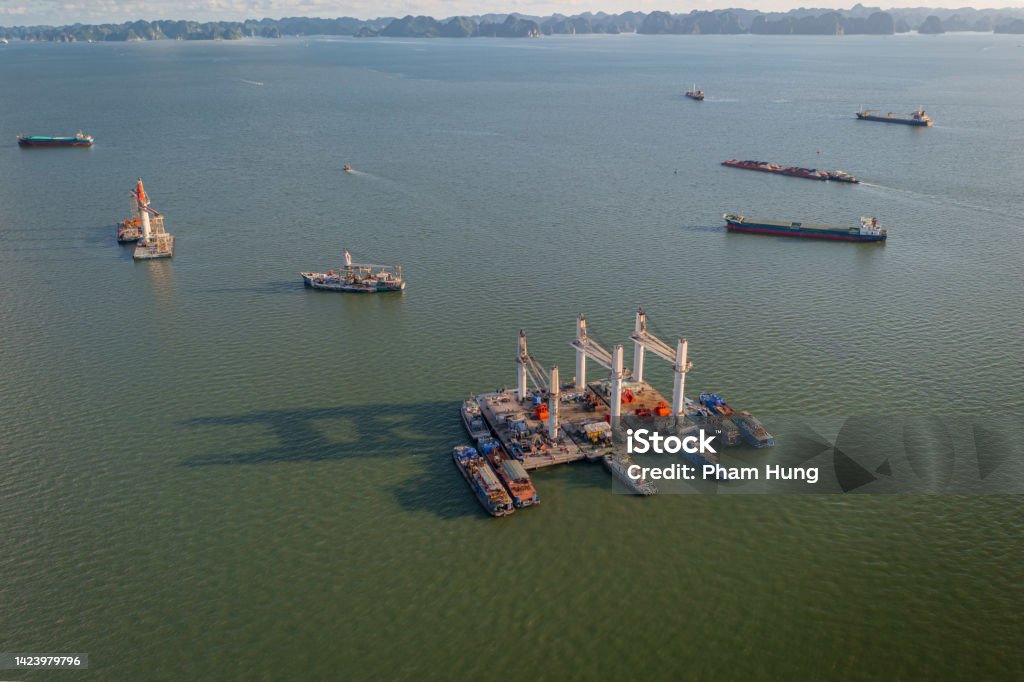 Lighter with heavy crane and logistic cargo ships on Ha Long bay Drone view of lighter with heavy crane and logistic cargo ships on Ha Long bay, Ha Long city, Quang Ninh province Aerial View Stock Photo