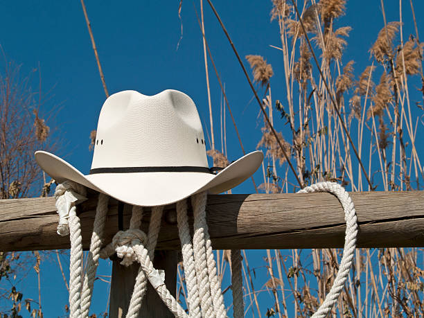 Cowboy hat in a fence White cowboy hat and rope in a country fence cowboy hat stock pictures, royalty-free photos & images