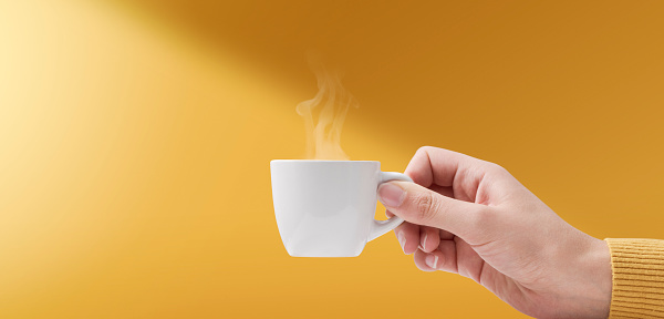 Female hand holding a cup of delicious hot coffee