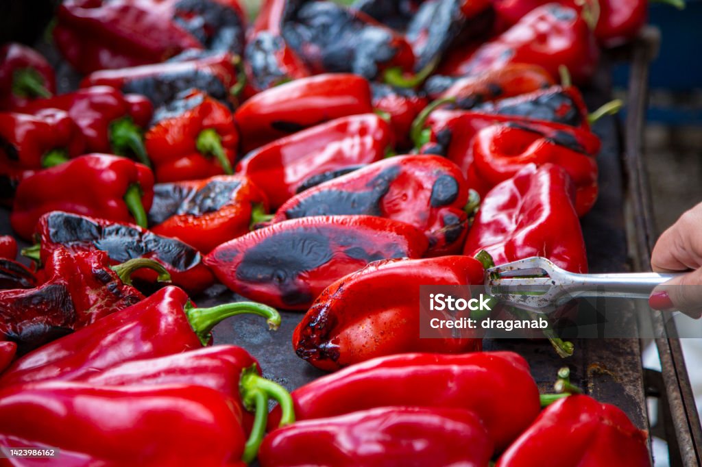 Ajvar homemaking in Serbia Close-up of a woman's hand roasting red peppers for ajvar. Roasting peppers outdoors on a wood burning stove. Serbian traditional process of making ajvar. Ajvar Stock Photo