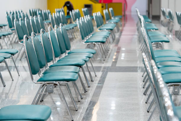 istock Many empty green leather chairs in a wide hall room, lights on. A floor reflect the objects. Give a feeling of emptiness. 1423988146