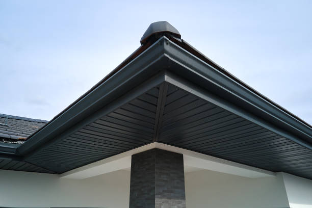 茶色の金属板のサイディングとスチール製の側溝の雨システムを備えた屋根を備えたハウスコーナー。屋根、建設、排水管の設置 - siding house plastic construction ストックフォトと画像