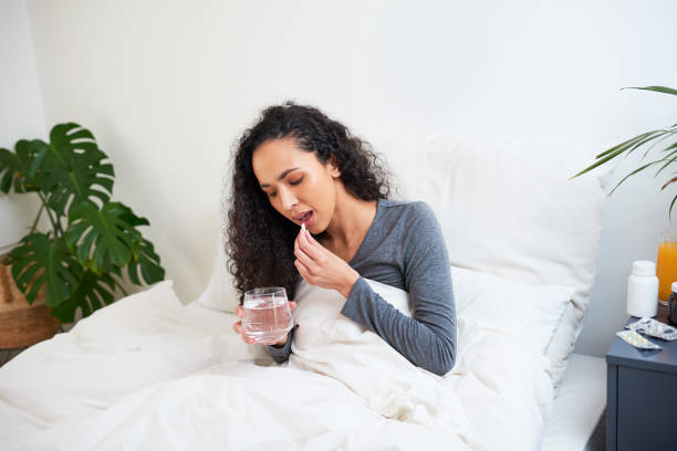 istock A young multi-ethnic woman takes a tablet in bed while sick with flu 1423995297